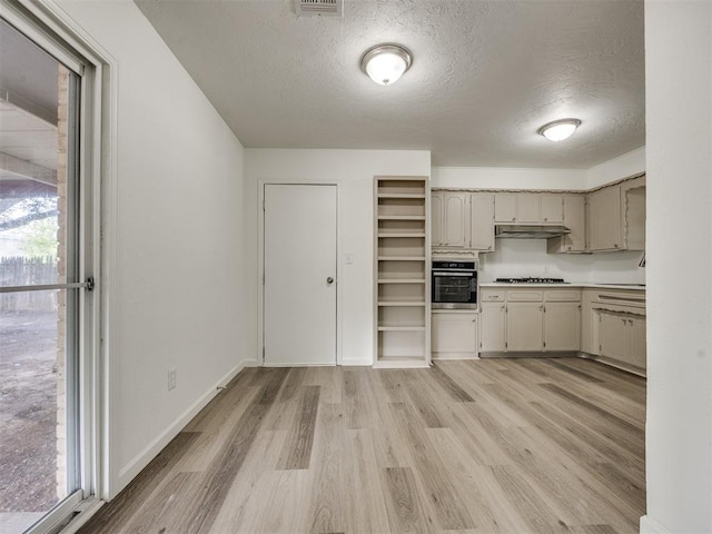 3044 S Madole Blvd, Oklahoma City, OK 73159 - kitchen with oven, gas stovetop, a textured ceiling, under cabinet range hood, and light wood-style flooring
