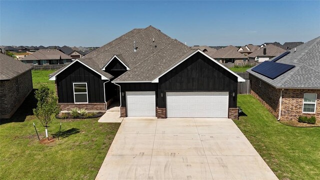 10617 Little Sallisaw Creek Dr, Yukon, OK 73099 - view of front of home with board and batten siding, a front lawn, driveway, and brick siding