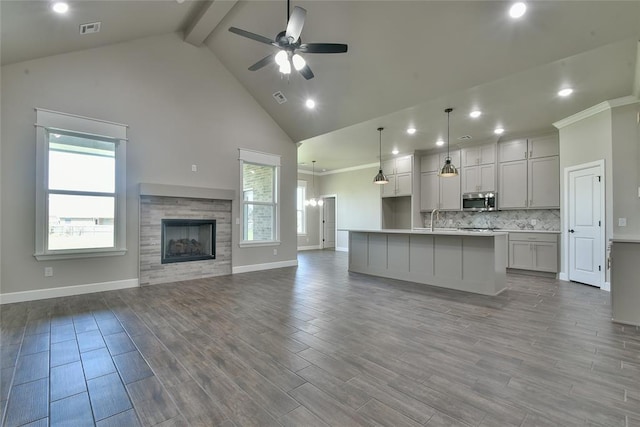 10617 Little Sallisaw Creek Dr, Yukon, OK 73099 - kitchen featuring stainless steel microwave, open floor plan, beamed ceiling, ceiling fan, and recessed lighting