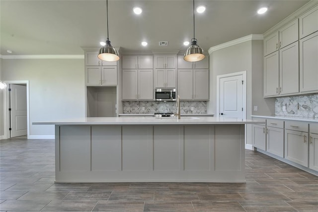 10617 Little Sallisaw Creek Dr, Yukon, OK 73099 - kitchen with stainless steel microwave, crown molding, backsplash, light countertops, and a kitchen island with sink