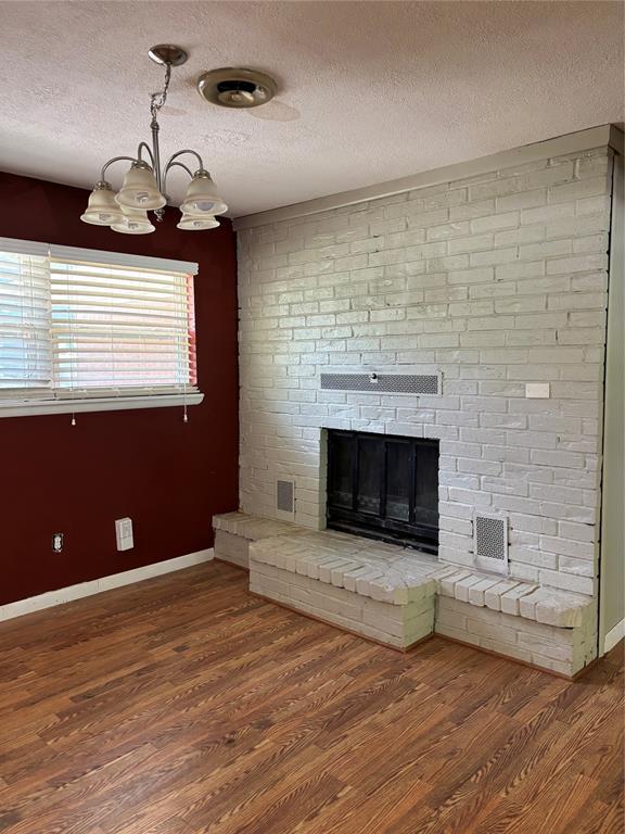 611 Garth Brooks Blvd, Yukon, OK 73099 - unfurnished living room featuring a chandelier, a textured ceiling, wood finished floors, and a fireplace