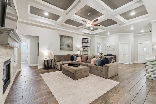 8040 Sweetgum St, Edmond, OK 73034 - living room with hardwood / wood-style flooring, a ceiling fan, a stone fireplace, ornamental molding, and coffered ceiling