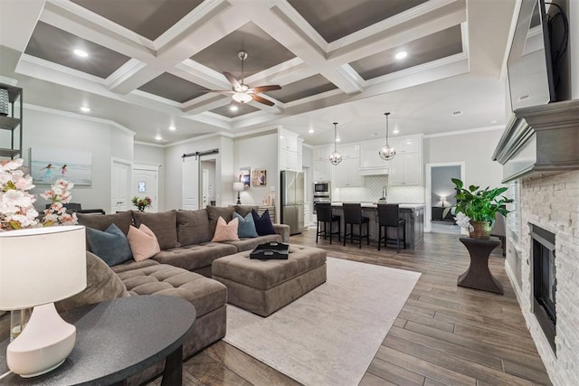 8040 Sweetgum St, Edmond, OK 73034 - living area featuring a barn door, crown molding, recessed lighting, coffered ceiling, and a stone fireplace