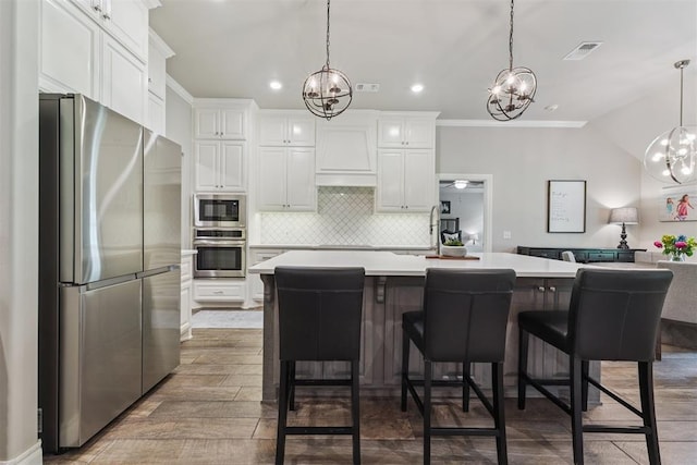 8040 Sweetgum St, Edmond, OK 73034 - kitchen with stainless steel appliances, a chandelier, custom exhaust hood, light countertops, and ornamental molding