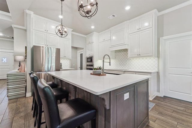 8040 Sweetgum St, Edmond, OK 73034 - kitchen featuring stainless steel appliances, a chandelier, ornamental molding, white cabinets, and backsplash