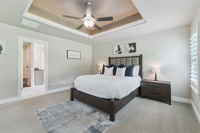 8040 Sweetgum St, Edmond, OK 73034 - carpeted bedroom with a tray ceiling, connected bathroom, ceiling fan, and multiple windows
