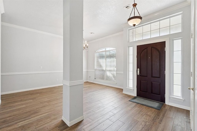 3343 Teton Cir, Norman, OK 73072 - entrance foyer with crown molding, ornate columns, wood finished floors, a chandelier, and a textured ceiling