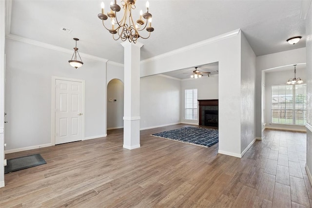 3343 Teton Cir, Norman, OK 73072 - unfurnished living room featuring arched walkways, healthy amount of natural light, a chandelier, wood finished floors, and crown molding
