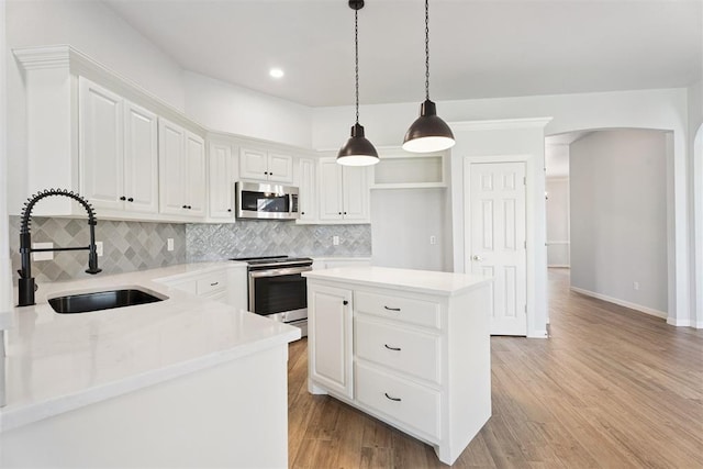 3343 Teton Cir, Norman, OK 73072 - kitchen featuring stainless steel appliances, arched walkways, backsplash, decorative light fixtures, and light countertops