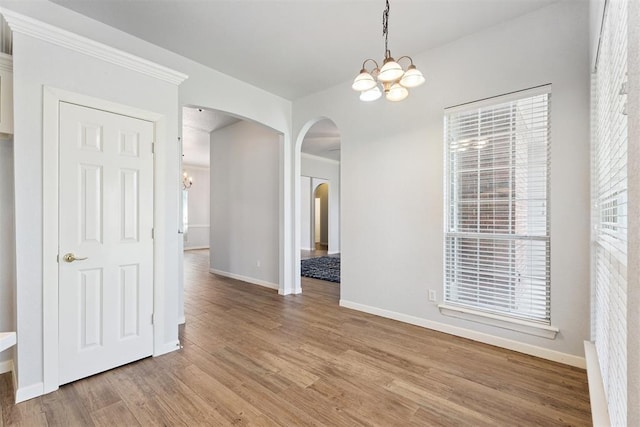 3343 Teton Cir, Norman, OK 73072 - unfurnished dining area with a chandelier, arched walkways, light wood-style floors, and plenty of natural light