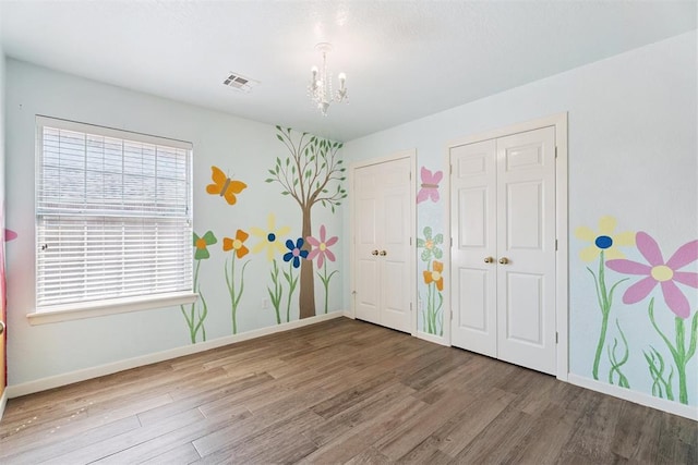 3343 Teton Cir, Norman, OK 73072 - unfurnished bedroom featuring wood finished floors, a chandelier, and two closets