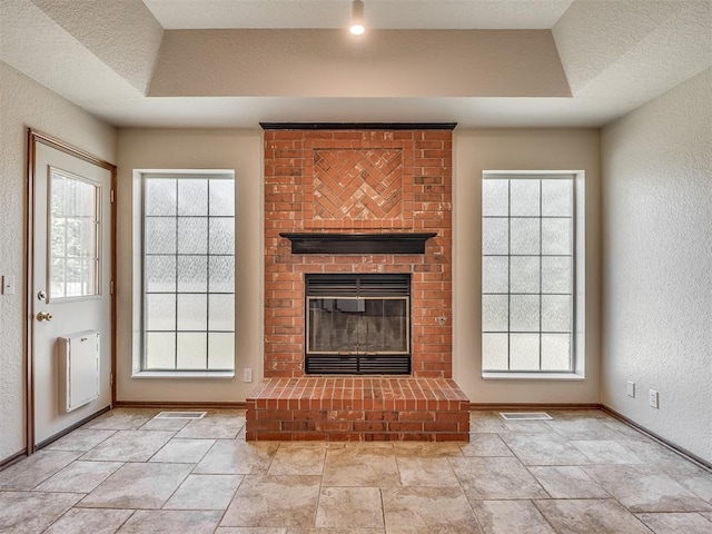 400 Ryan Way, Edmond, OK 73003 - unfurnished living room featuring a fireplace, plenty of natural light, and a textured wall