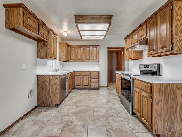 400 Ryan Way, Edmond, OK 73003 - kitchen featuring stainless steel appliances, under cabinet range hood, brown cabinetry, stone finish floors, and a textured ceiling