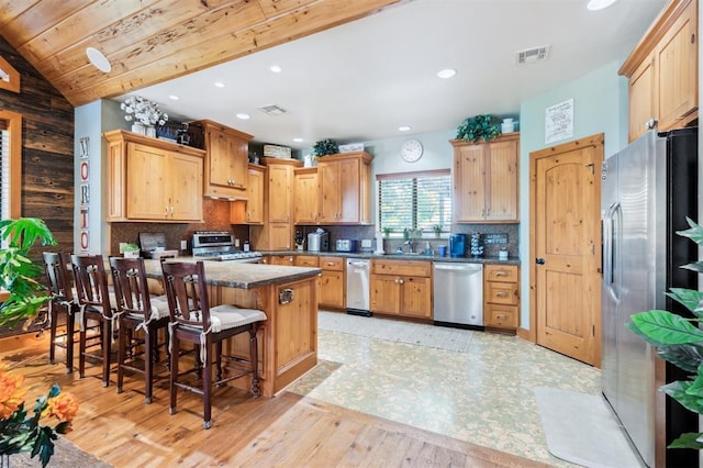 39 E Shore Dr, Arcadia, OK 73007 - kitchen featuring stainless steel appliances, a kitchen bar, light wood finished floors, decorative backsplash, and dark countertops