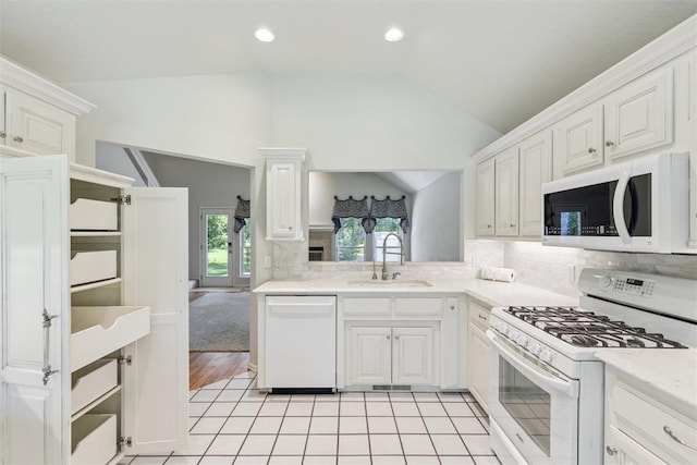 812 Old Bugle Rd, Edmond, OK 73003 - kitchen with white appliances, vaulted ceiling, light countertops, white cabinetry, and backsplash