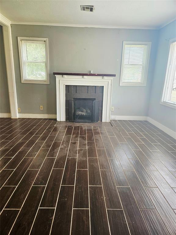 934 E Elm St, Altus, OK 73521 - unfurnished living room featuring wood finished floors, crown molding, and a tiled fireplace