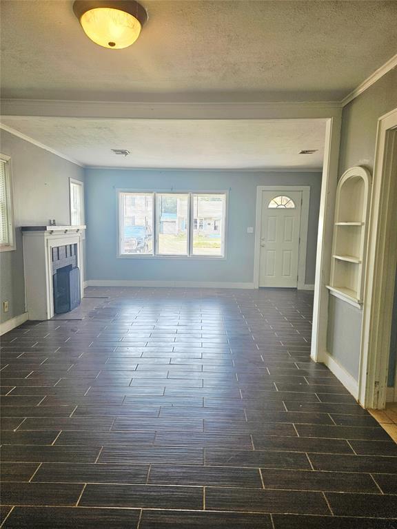 934 E Elm St, Altus, OK 73521 - unfurnished living room with crown molding, a textured ceiling, and a fireplace