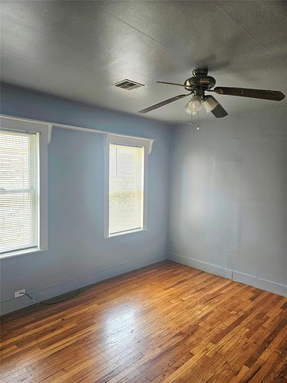 934 E Elm St, Altus, OK 73521 - empty room with wood-type flooring, plenty of natural light, and ceiling fan