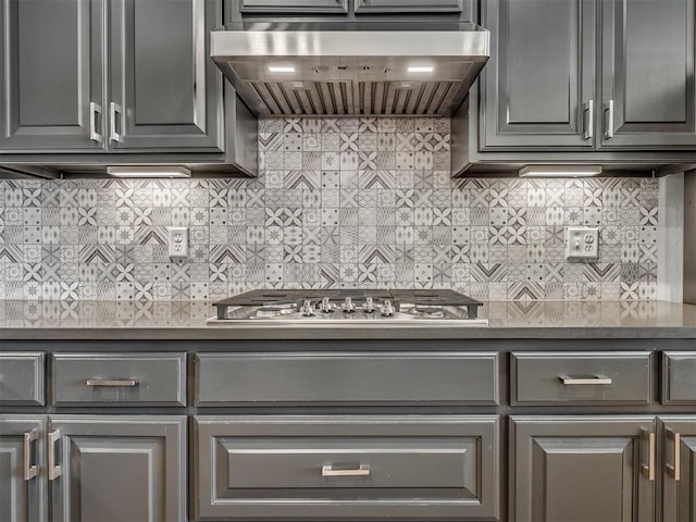 3760 Black Mesa Rd, Norman, OK 73071 - kitchen featuring wall chimney exhaust hood, dark countertops, gray cabinetry, stainless steel gas cooktop, and tasteful backsplash