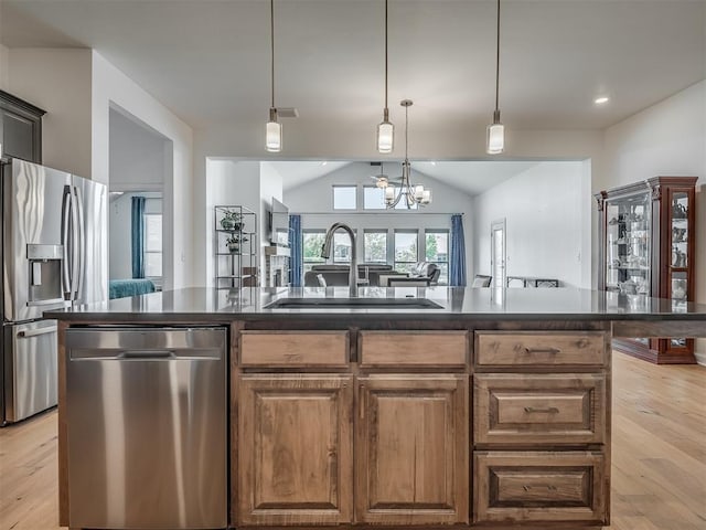 3760 Black Mesa Rd, Norman, OK 73071 - kitchen featuring appliances with stainless steel finishes, dark countertops, light wood-style flooring, lofted ceiling, and a center island with sink