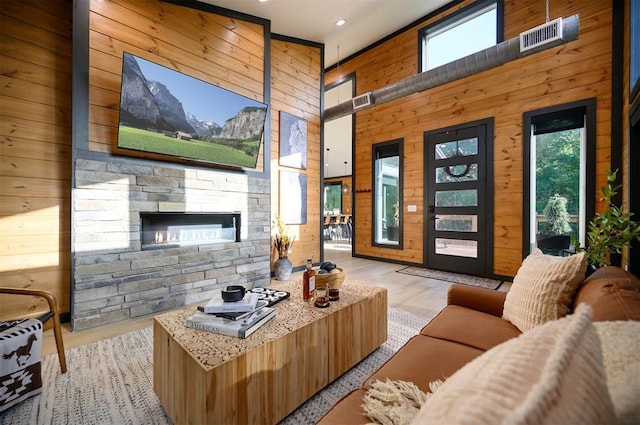 105 S Spruce Trl, Broken Bow, OK 74728 - living area with wood walls, a stone fireplace, wood finished floors, recessed lighting, and a towering ceiling
