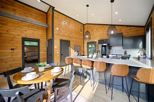 105 S Spruce Trl, Broken Bow, OK 74728 - kitchen with stainless steel appliances, light countertops, wooden walls, a peninsula, and wall chimney exhaust hood