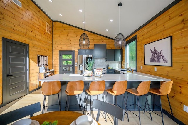 105 S Spruce Trl, Broken Bow, OK 74728 - kitchen with appliances with stainless steel finishes, wood walls, lofted ceiling, light countertops, and a kitchen breakfast bar