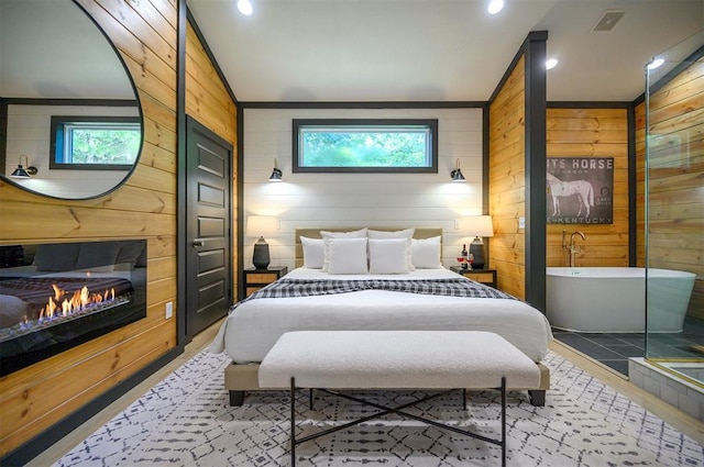 105 S Spruce Trl, Broken Bow, OK 74728 - bedroom with wood walls, multiple windows, vaulted ceiling, a glass covered fireplace, and recessed lighting