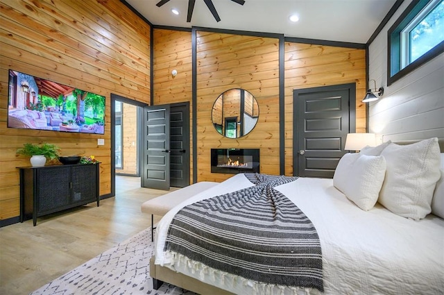 105 S Spruce Trl, Broken Bow, OK 74728 - bedroom featuring wooden walls, a glass covered fireplace, recessed lighting, and wood finished floors