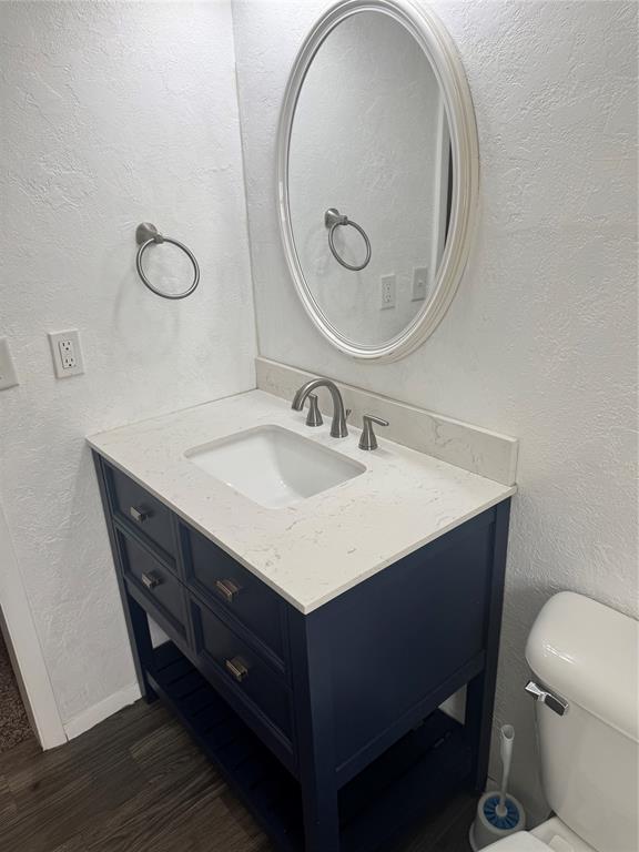 818 W Watts St, El Reno, OK 73036 - half bath featuring vanity, wood finished floors, and a textured wall