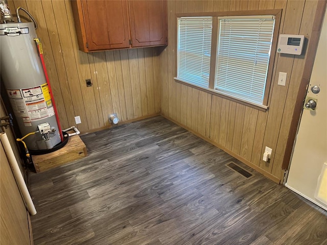 818 W Watts St, El Reno, OK 73036 - washroom featuring water heater, dark wood-style floors, cabinet space, and wood walls