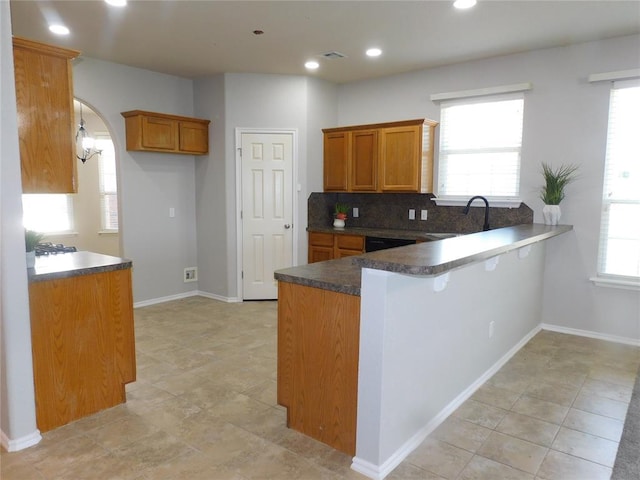 6036 SE 66th St, Oklahoma City, OK 73135 - kitchen featuring brown cabinets, a peninsula, dark countertops, tasteful backsplash, and arched walkways