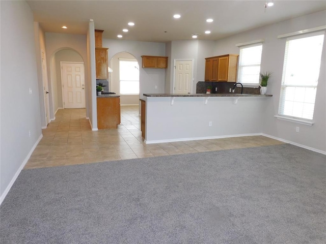 6036 SE 66th St, Oklahoma City, OK 73135 - kitchen featuring arched walkways, light colored carpet, recessed lighting, dark countertops, and brown cabinets