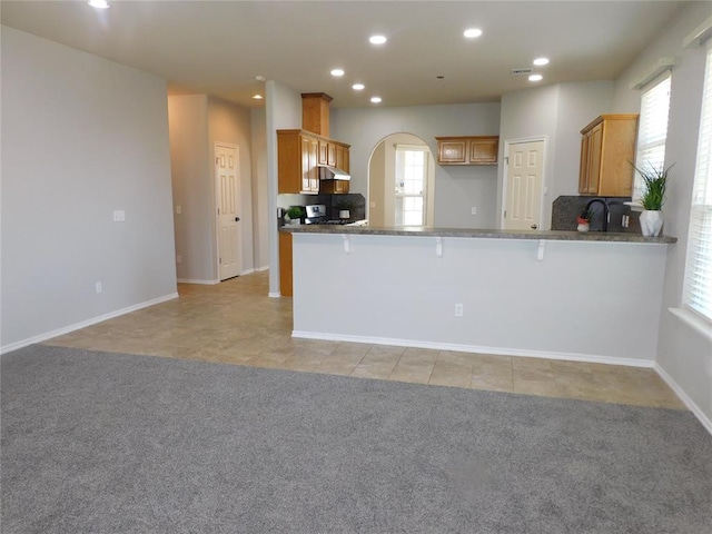 6036 SE 66th St, Oklahoma City, OK 73135 - kitchen with a peninsula, under cabinet range hood, recessed lighting, a breakfast bar, and gas stove