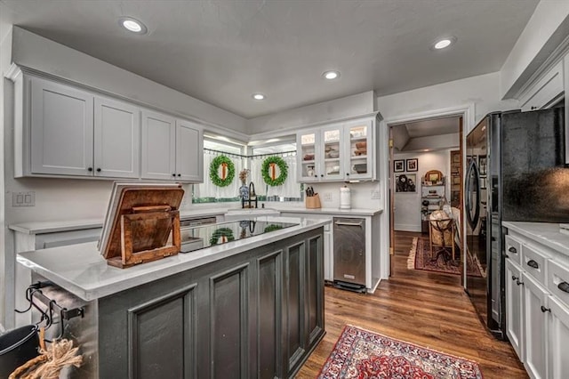 1601 Hazelhurst, Edmond, OK 73013 - kitchen with light countertops, black appliances, dark wood-style flooring, glass insert cabinets, and recessed lighting