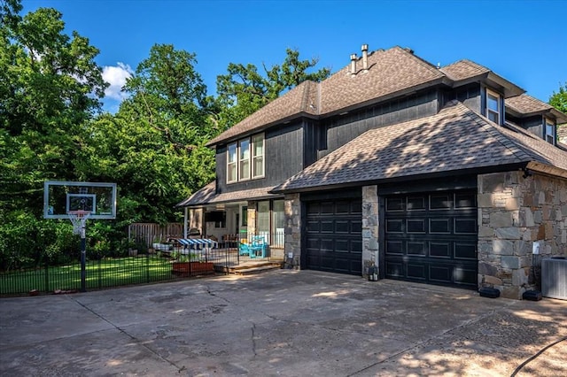 1601 Hazelhurst, Edmond, OK 73013 - view of front facade with a garage, stone siding, concrete driveway, and a shingled roof
