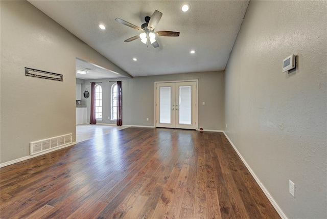 1021 SW 1st St, Moore, OK 73160 - unfurnished living room with a textured wall, wood finished floors, ceiling fan, french doors, and vaulted ceiling