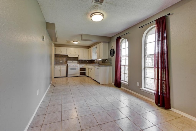 1021 SW 1st St, Moore, OK 73160 - kitchen featuring white appliances, a textured ceiling, light tile patterned floors, white cabinetry, and under cabinet range hood