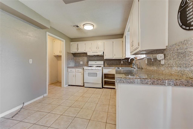 1021 SW 1st St, Moore, OK 73160 - kitchen with white range with gas cooktop, under cabinet range hood, backsplash, light tile patterned floors, and white cabinetry