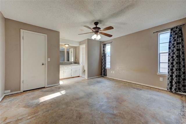 1021 SW 1st St, Moore, OK 73160 - unfurnished bedroom featuring multiple windows, a textured ceiling, concrete flooring, connected bathroom, and ceiling fan
