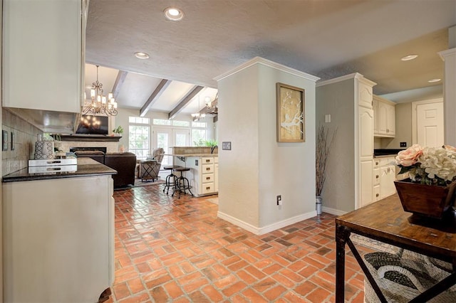 5305 Circle Gln, Edmond, OK 73025 - kitchen featuring a chandelier, dark countertops, a fireplace, open floor plan, and brick floors
