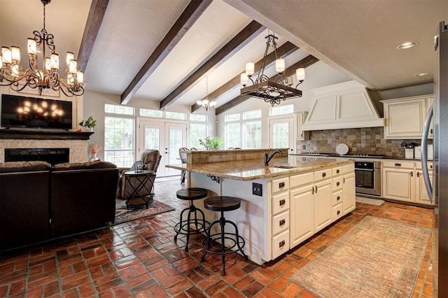 5305 Circle Gln, Edmond, OK 73025 - kitchen with a chandelier, custom exhaust hood, open floor plan, oven, and a breakfast bar