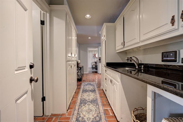 5305 Circle Gln, Edmond, OK 73025 - kitchen with recessed lighting, white cabinets, dark stone countertops, and brick flooring