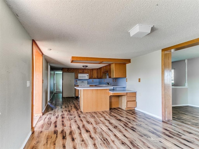2618 NW Apache Rd, Piedmont, OK 73078 - kitchen with white appliances, a peninsula, a textured ceiling, light wood finished floors, and light countertops
