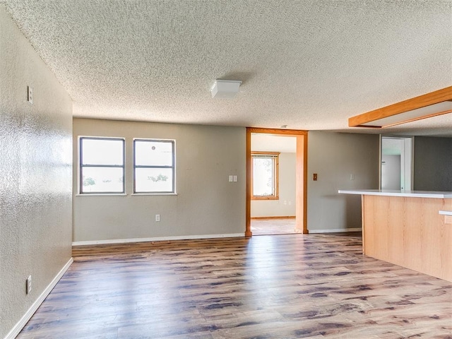 2618 NW Apache Rd, Piedmont, OK 73078 - unfurnished living room featuring wood finished floors, a textured ceiling, and a textured wall