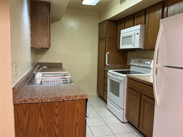 600 NW 4th St Unit 305N, Oklahoma City, OK 73102 - kitchen featuring white appliances, light tile patterned floors, and brown cabinets