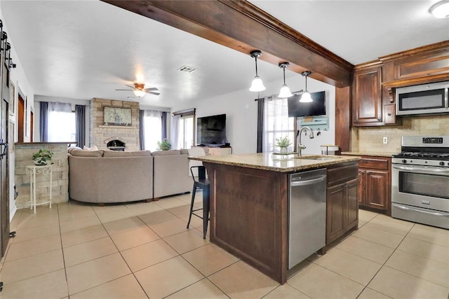 7007 NW 61st St, Bethany, OK 73008 - kitchen with appliances with stainless steel finishes, light stone counters, light tile patterned flooring, and ceiling fan