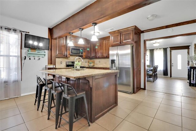 7007 NW 61st St, Bethany, OK 73008 - kitchen featuring appliances with stainless steel finishes, light tile patterned flooring, light stone counters, backsplash, and a breakfast bar
