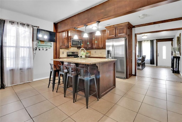 7007 NW 61st St, Bethany, OK 73008 - kitchen featuring appliances with stainless steel finishes, light tile patterned floors, hanging light fixtures, a kitchen breakfast bar, and decorative backsplash