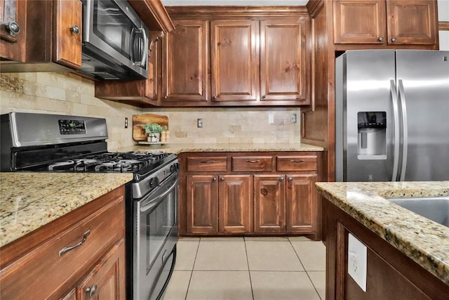 7007 NW 61st St, Bethany, OK 73008 - kitchen with appliances with stainless steel finishes, light tile patterned floors, light stone countertops, and backsplash
